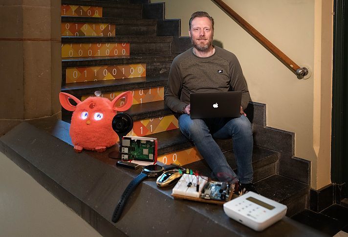 Erik Rutkens met macbook op trap, voorgrond slimme apparatuur
